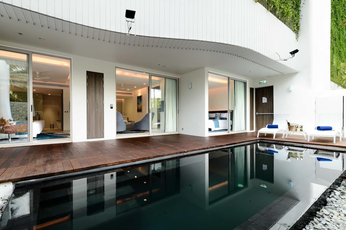 A modern house with a swimming pool, large sliding glass doors, and a deck area with lounge chairs.