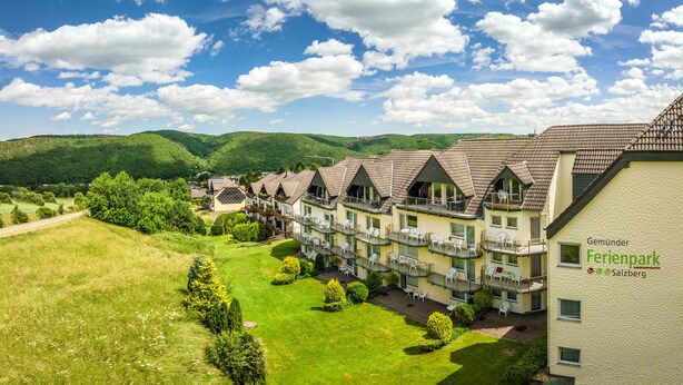 Un hôtel doté de nombreux balcons, d’une pelouse bien entretenue et offrant une vue sur un paysage montagneux.