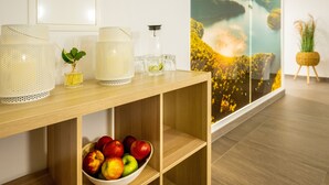 Une console en bois agrémentée de lampes décoratives, d’un petit vase avec une plante et d’un bol de pommes.