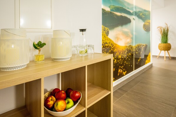 Una consola de madera con lámparas decorativas, un pequeño florero con una planta y un cuenco de manzanas.