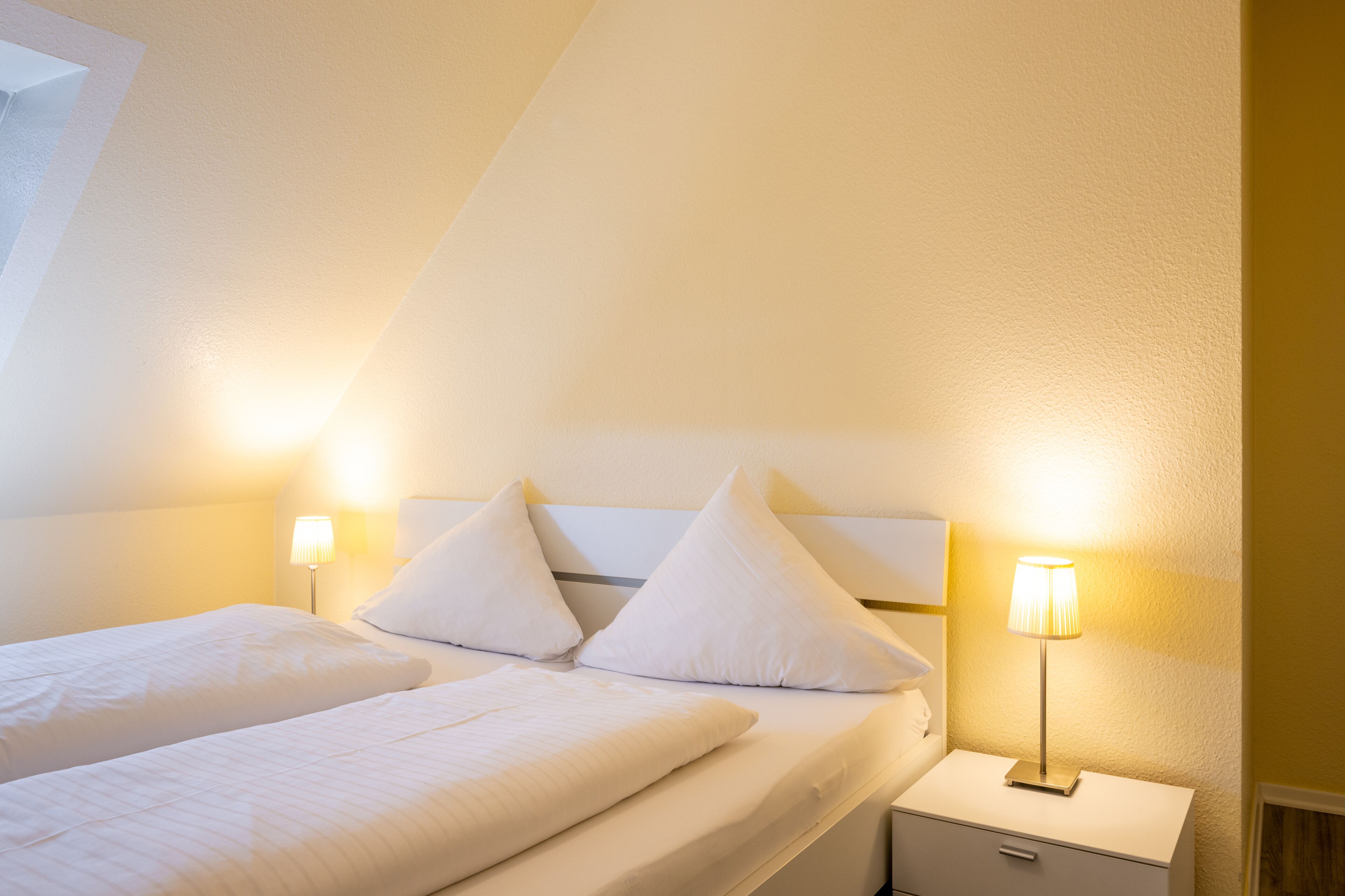 Una habitación de hotel con dos camas, una mesita de noche y dos lámparas de noche.