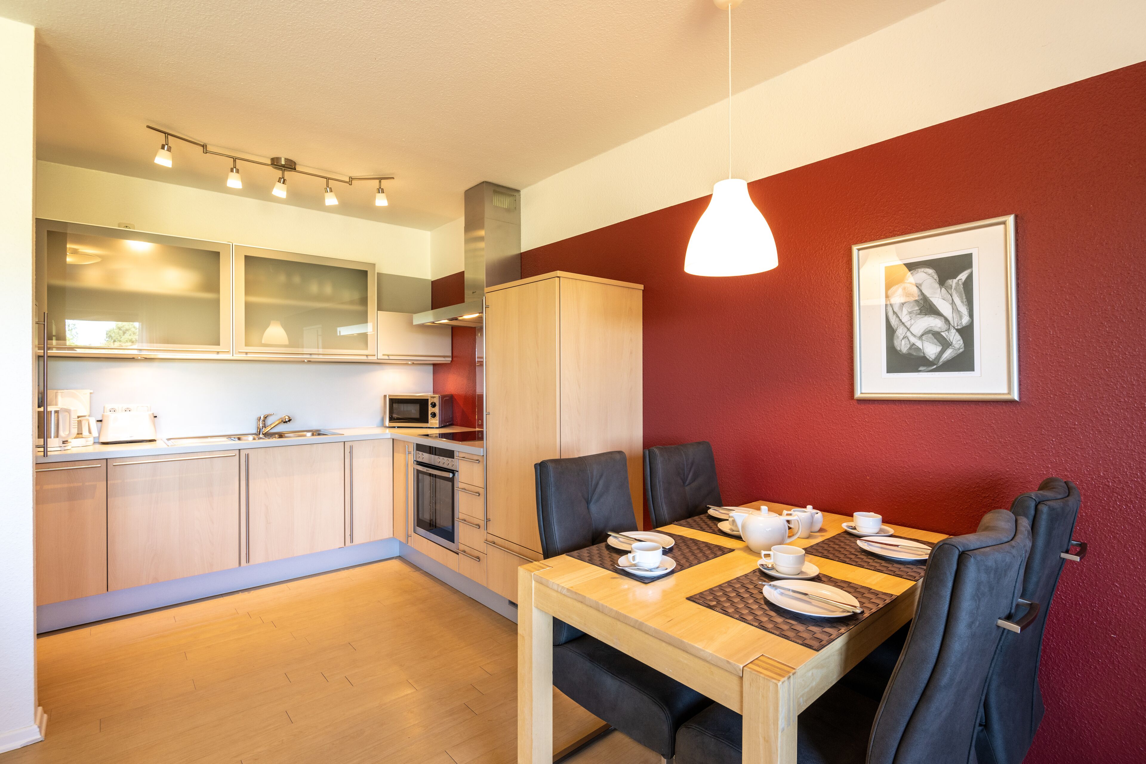 A modern kitchen with a dining area. It includes a wooden table, chairs, and a microwave.