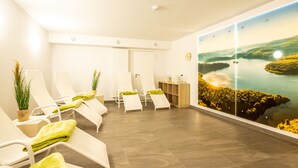 Une salle de spa équipée de fauteuils inclinables, d’un téléviseur fixé au mur et offrant une vue sur un lac.