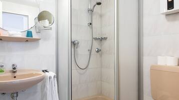 A modern bathroom with a glass-enclosed shower, a sink, and a toilet.