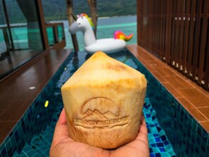 A hand holding a carved stone with a mountain design, a pool, and a unicorn float in the background.