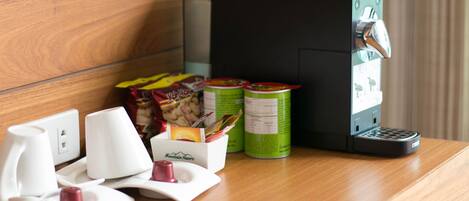 A wooden counter with a coffee machine, a white mug, a box labeled "Mountain Resort," and two green cans.