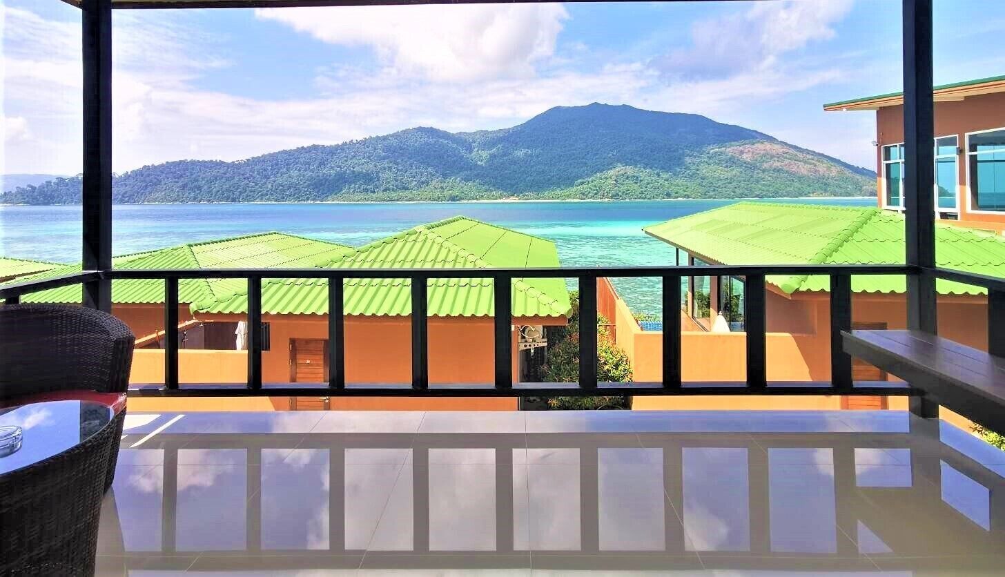 A balcony with a view of a mountain and turquoise waters.