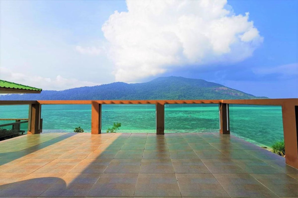A terrace with a view of a mountain and the sea.