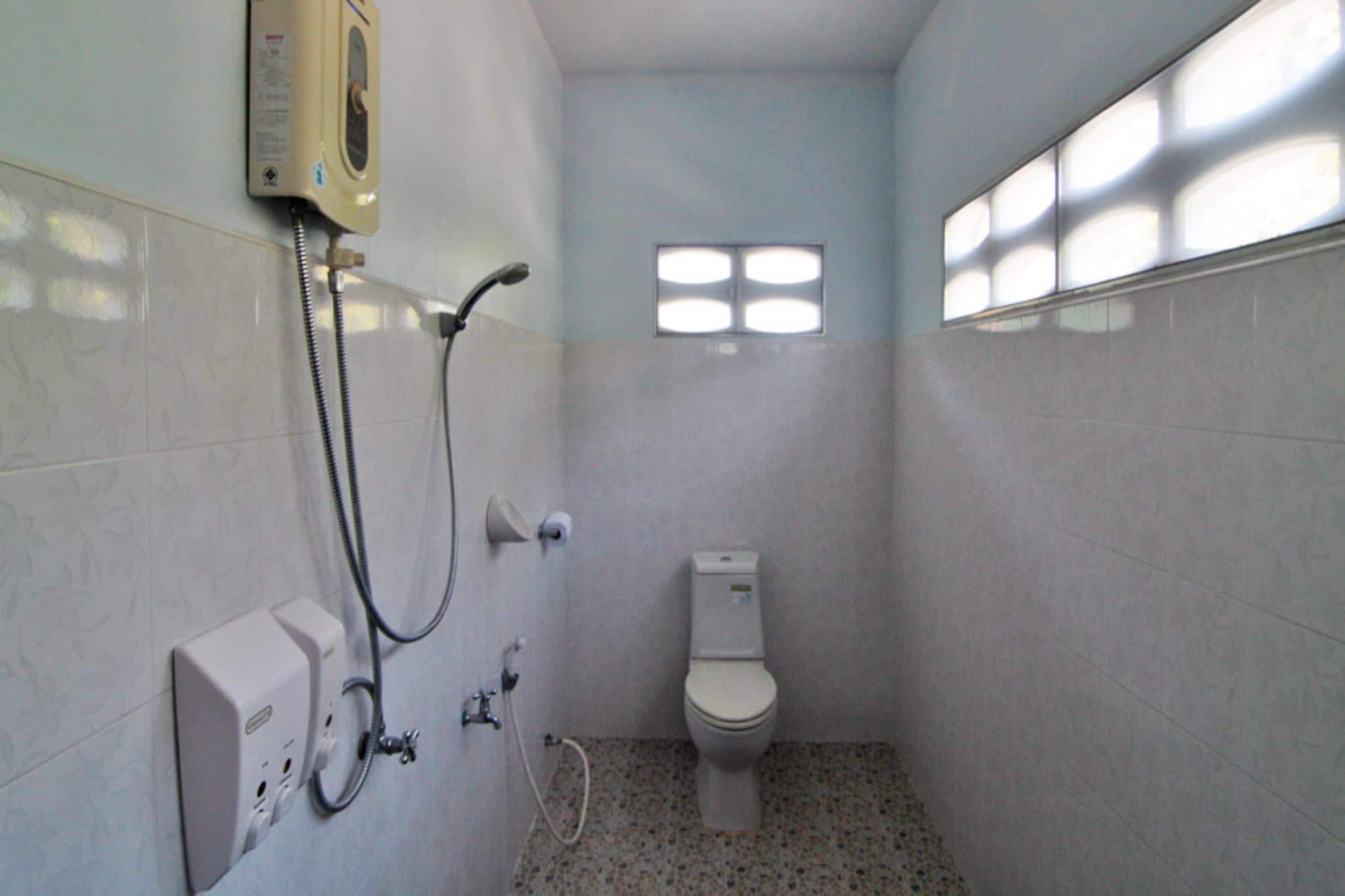 Un baño pequeño y funcional con inodoro, cabina de ducha y ventana.