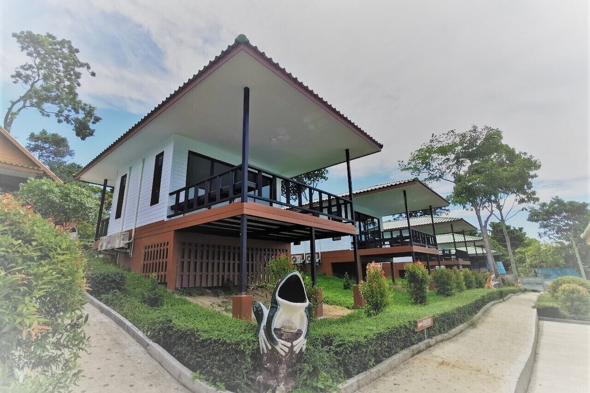 A two-story building with a flat roof and a balcony on the upper floor.