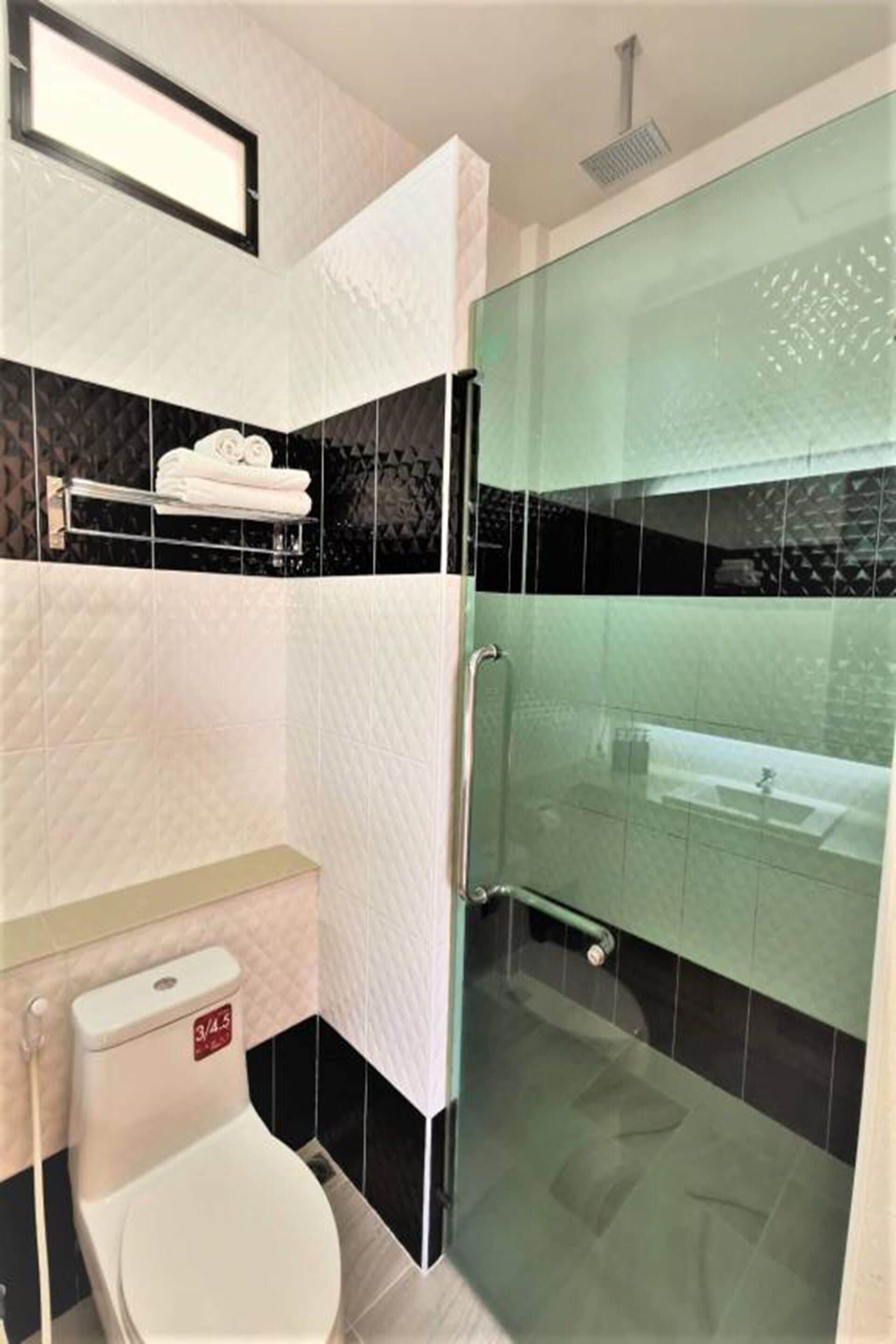 A modern bathroom with a glass shower enclosure, a toilet, and a sink.