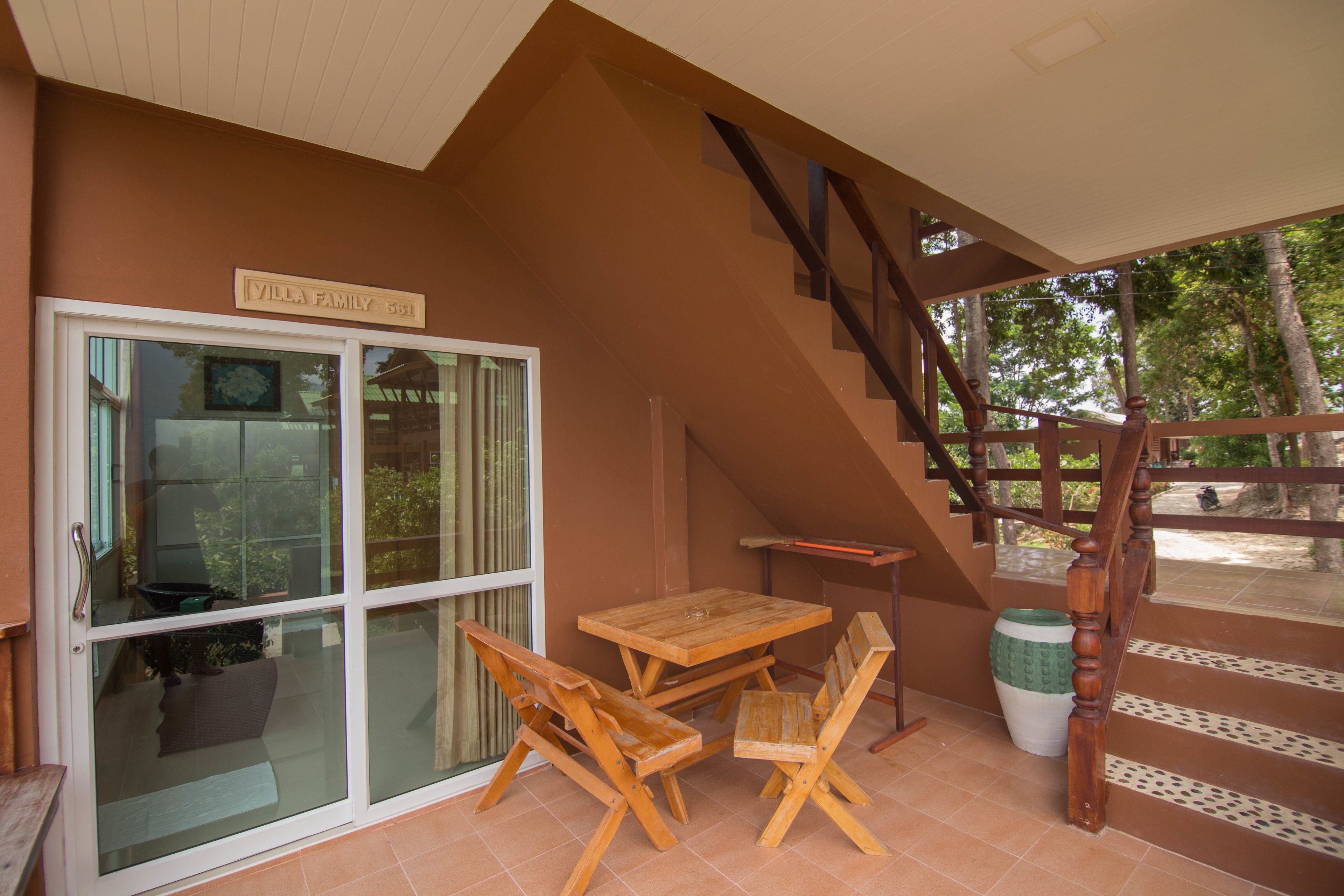 Un patio con una mesa y sillas de madera, una puerta corrediza de vidrio y una escalera.