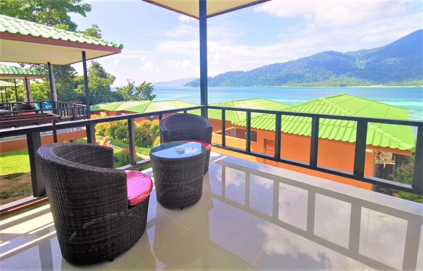 A balcony with wicker furniture and a view of a coastal landscape.