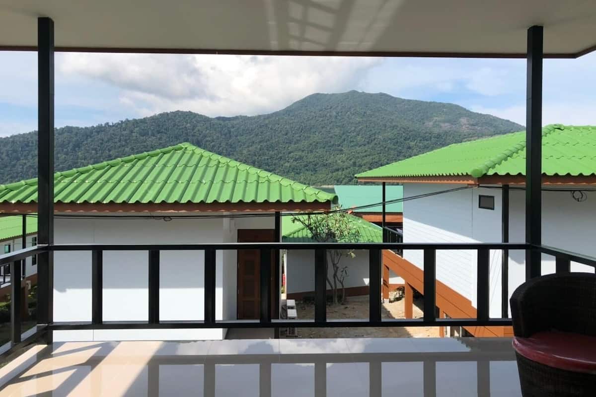 A balcony with a view of houses with green roofs and a mountain in the background.