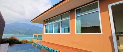 Une maison moderne dotée d’une piscine, de grandes fenêtres et offrant une vue sur les montagnes.