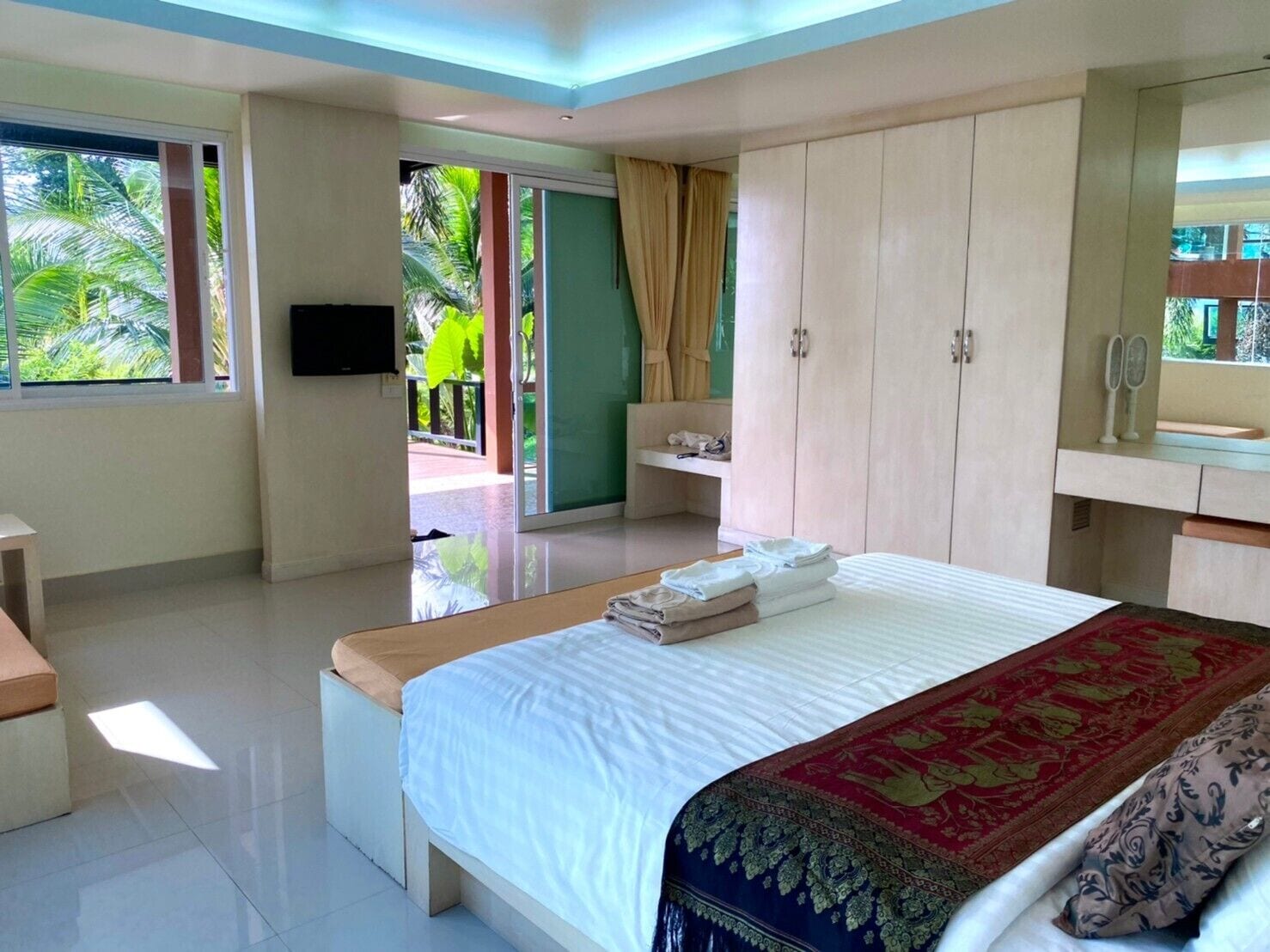 A hotel room with a bed, a TV, a wardrobe, a bathroom, and a view of the outdoors.