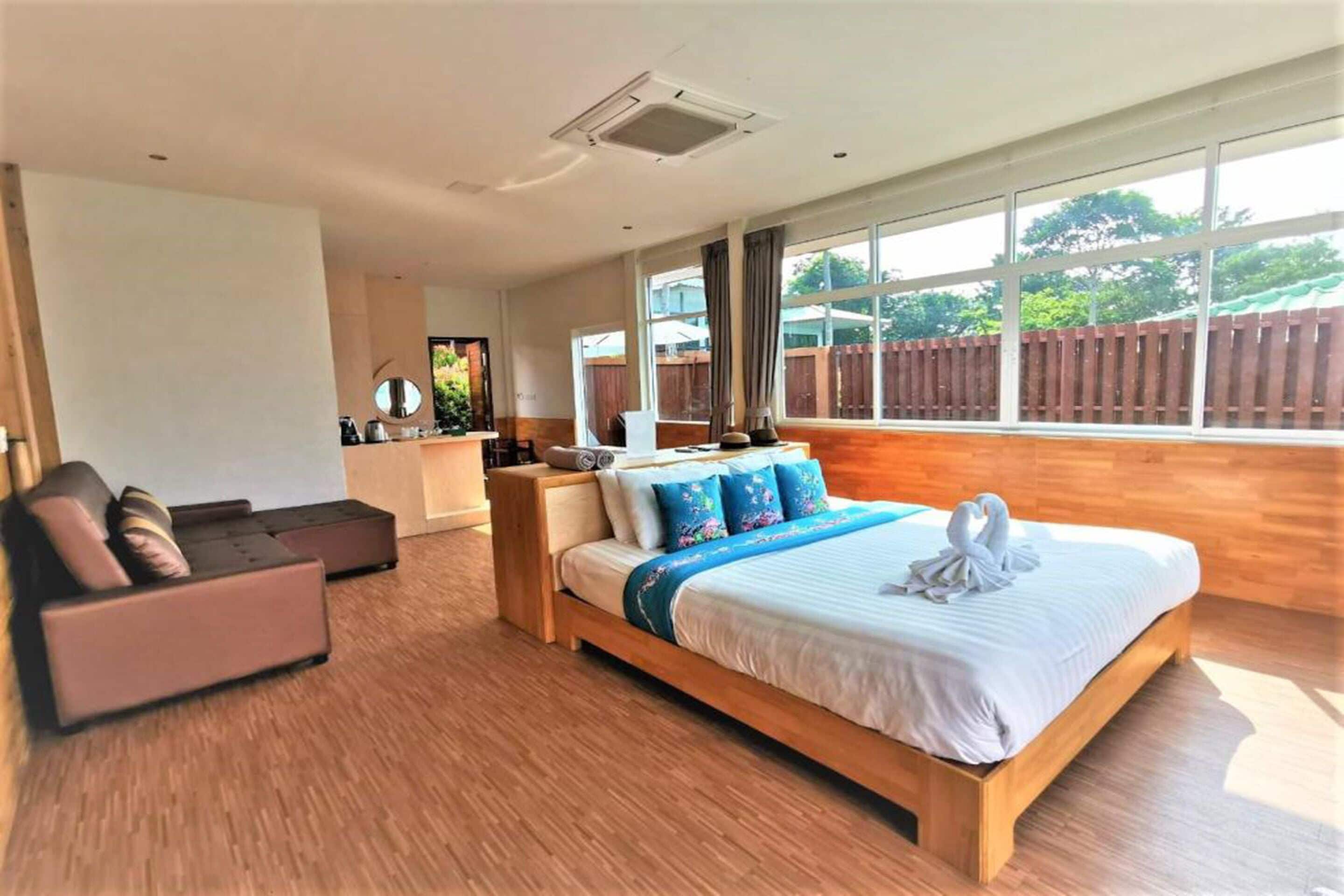 A spacious bedroom with a large bed, a sofa, and a desk area.