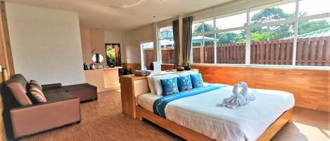 A spacious bedroom with a large bed, a sofa, and a desk area.