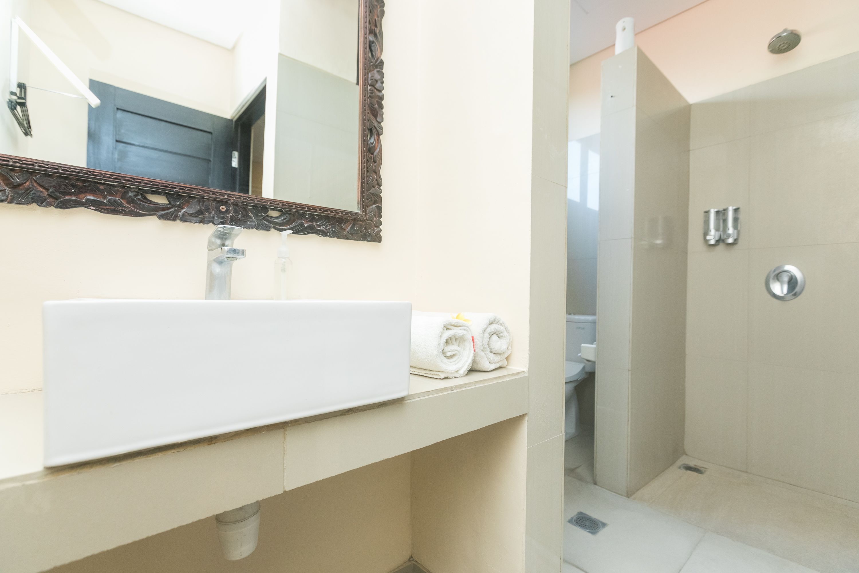 A bathroom with a white sink, a mirror with an ornate frame, and a shower area.