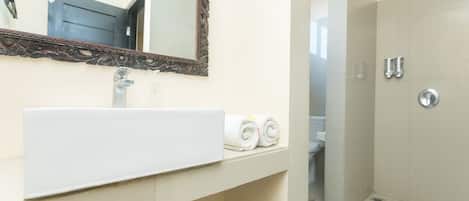 A bathroom with a white sink, a mirror with an ornate frame, and a shower area.