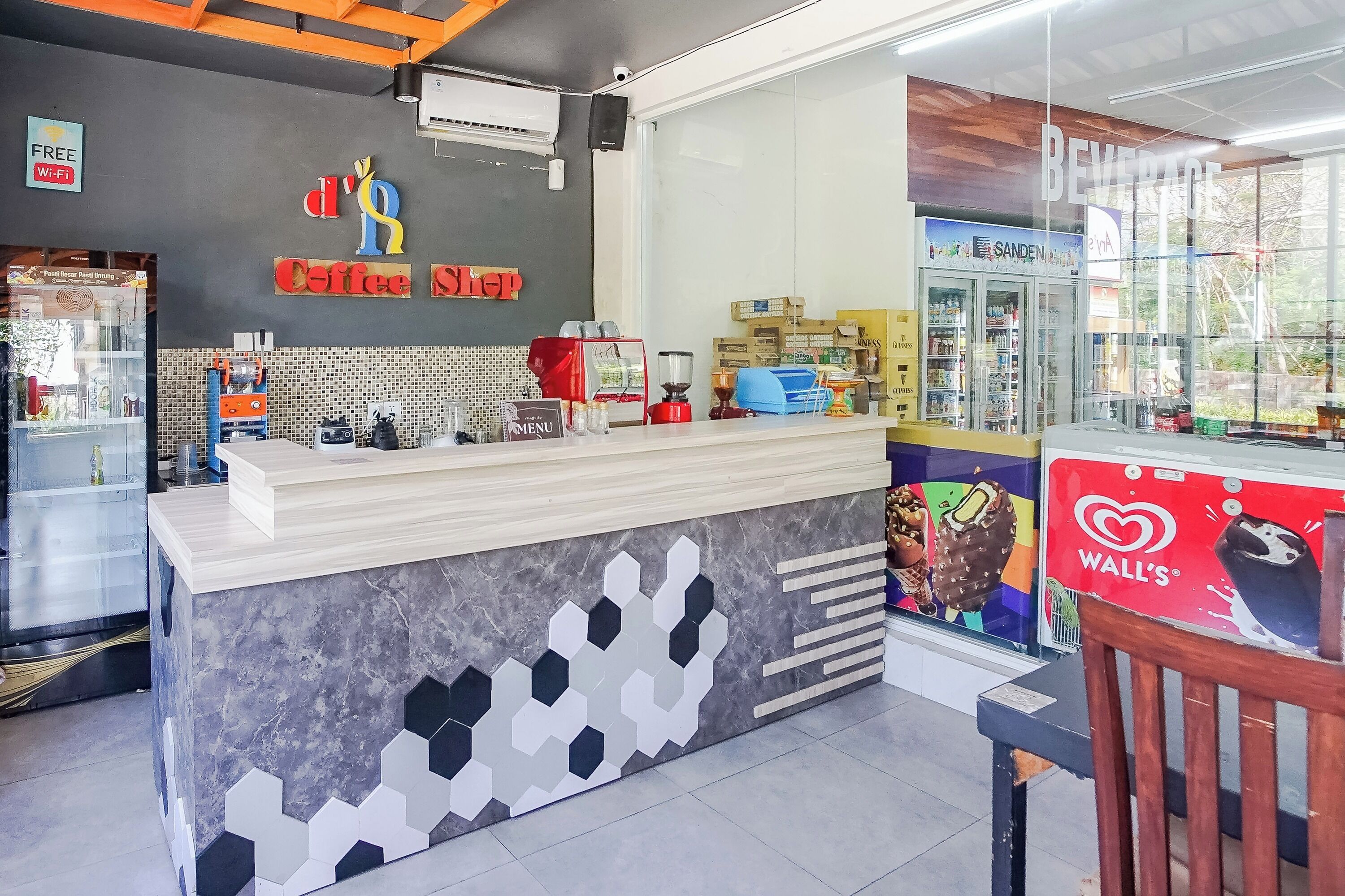 A coffee shop counter with a modern design, a menu board, and a refrigerator.