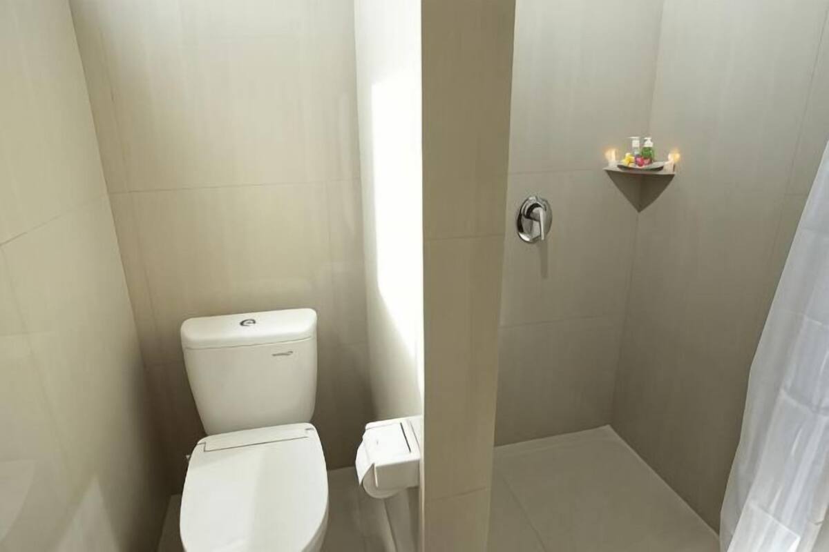 A bathroom with a toilet, a shower, and a shelf with toiletries.