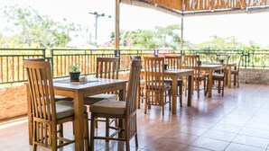 Un patio al aire libre con mesas y sillas de madera, una planta en maceta y vistas a la vegetación.
