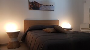 A bedroom with a bed, two bedside lamps, a headboard, and a wall-mounted picture. - B&B BuonaLuna (Palermo)