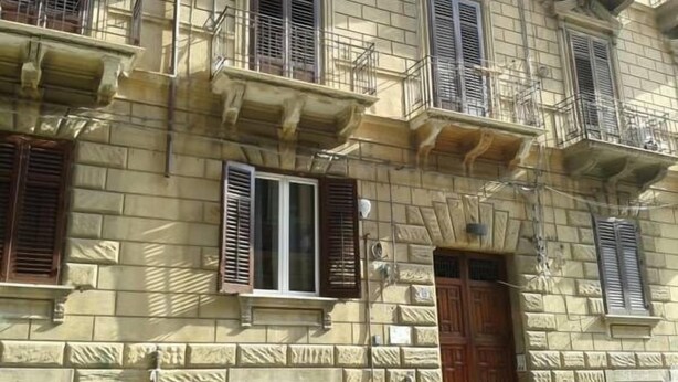 A multi-story building with stone facade, wooden shutters, and balconies. - B&B BuonaLuna (Palermo)