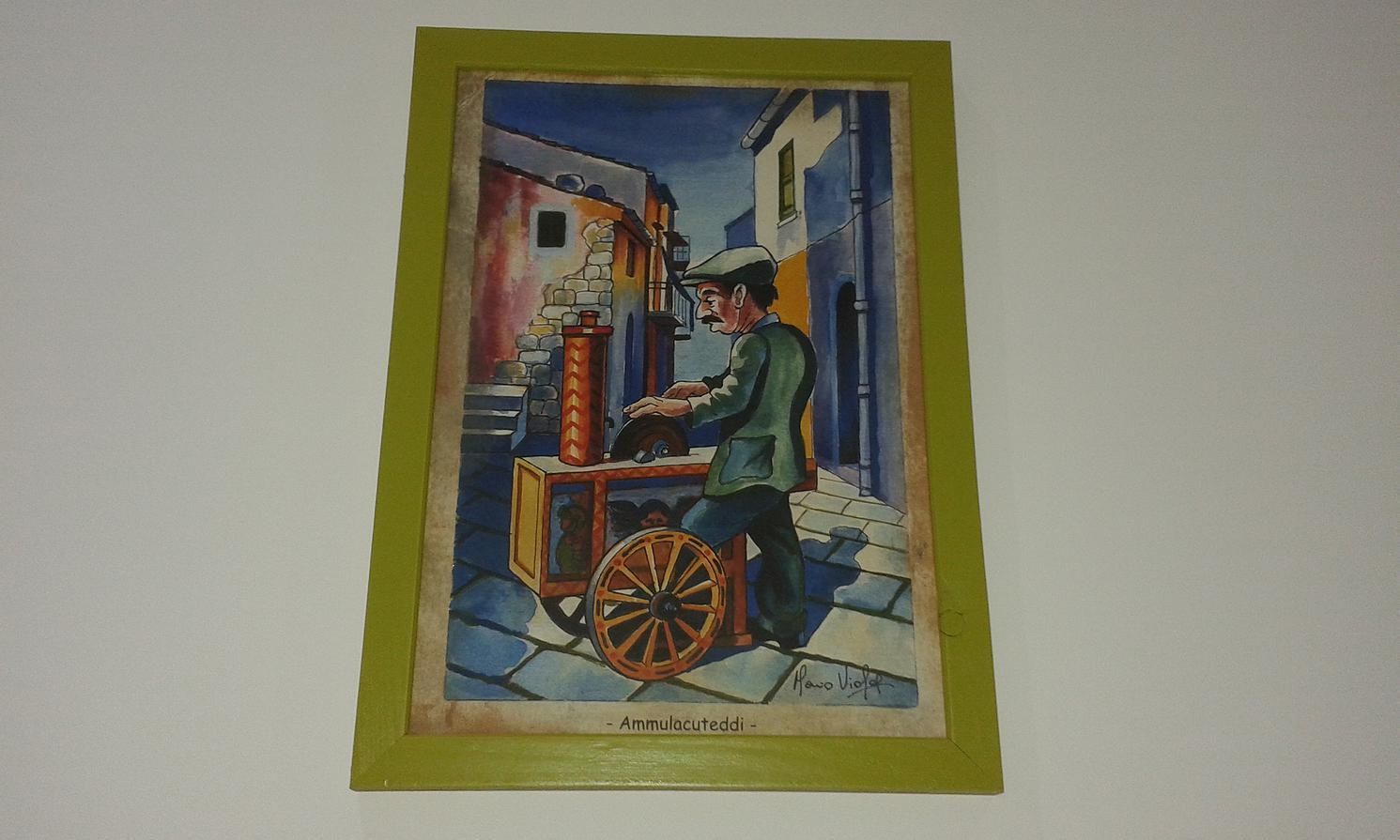 A framed artwork depicting a street scene with a man operating a cart.