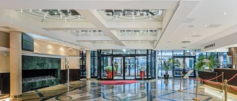 Um lobby moderno com entrada de vidro, lareira de mármore e piso estampado.