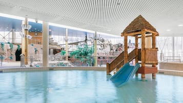 Um parque aquático interno com uma estrutura de recreação de madeira, escorregas e uma piscina grande.