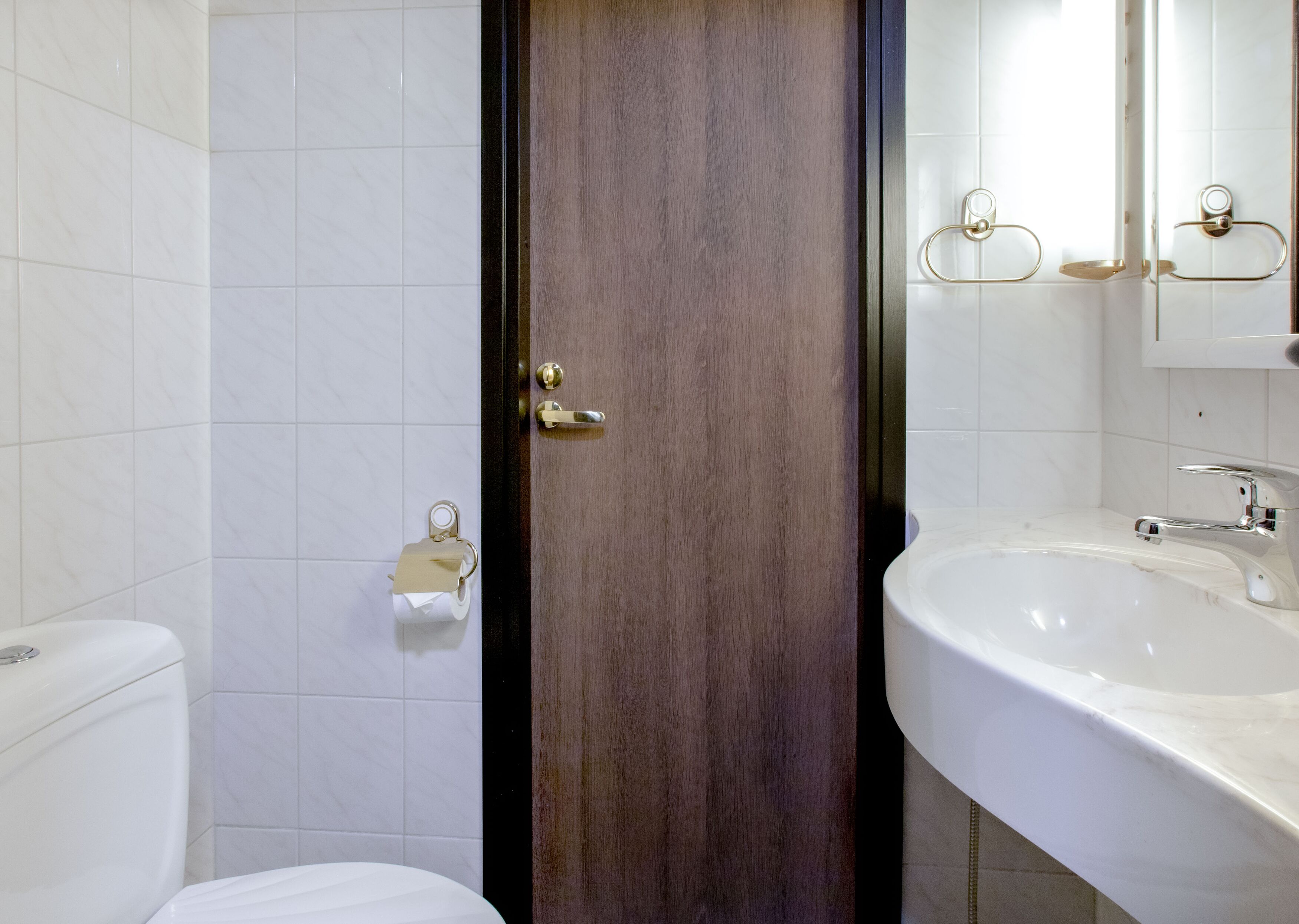 Un baño con inodoro, lavamanos y espejo.