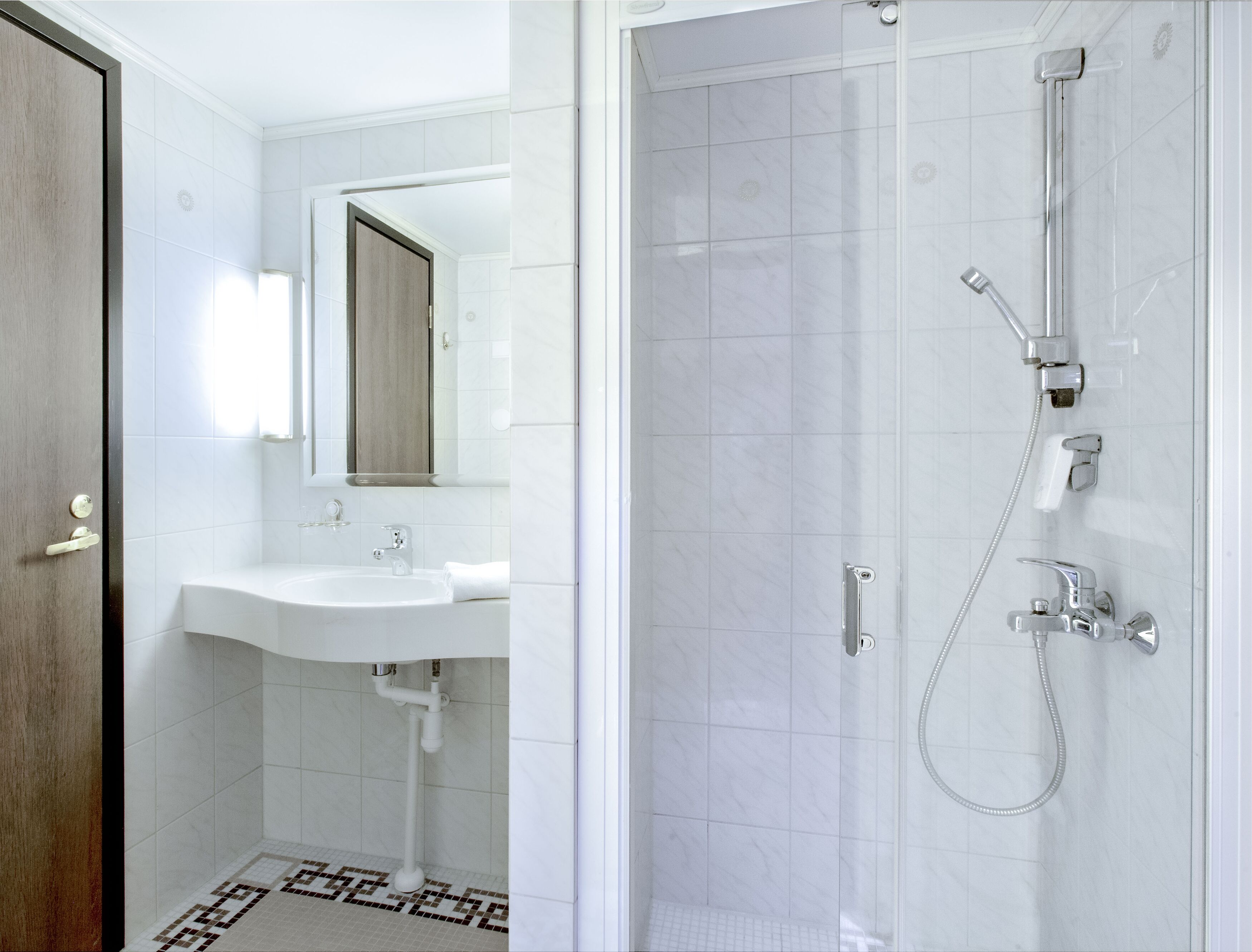 A bathroom with a sink, mirror, and shower.