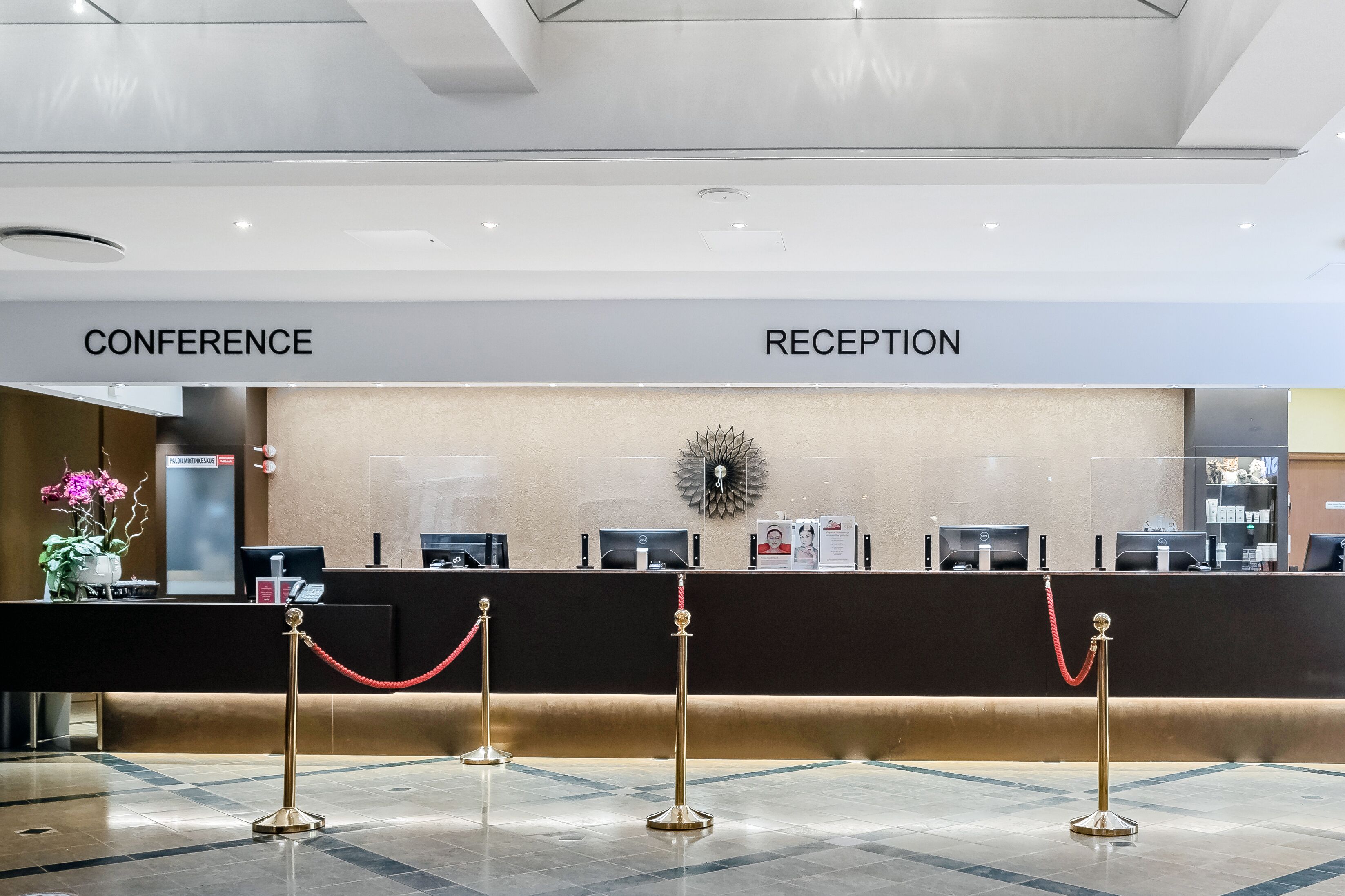 Zona de recepción de un hotel con mostrador, área de conferencias y cartel de recepción.