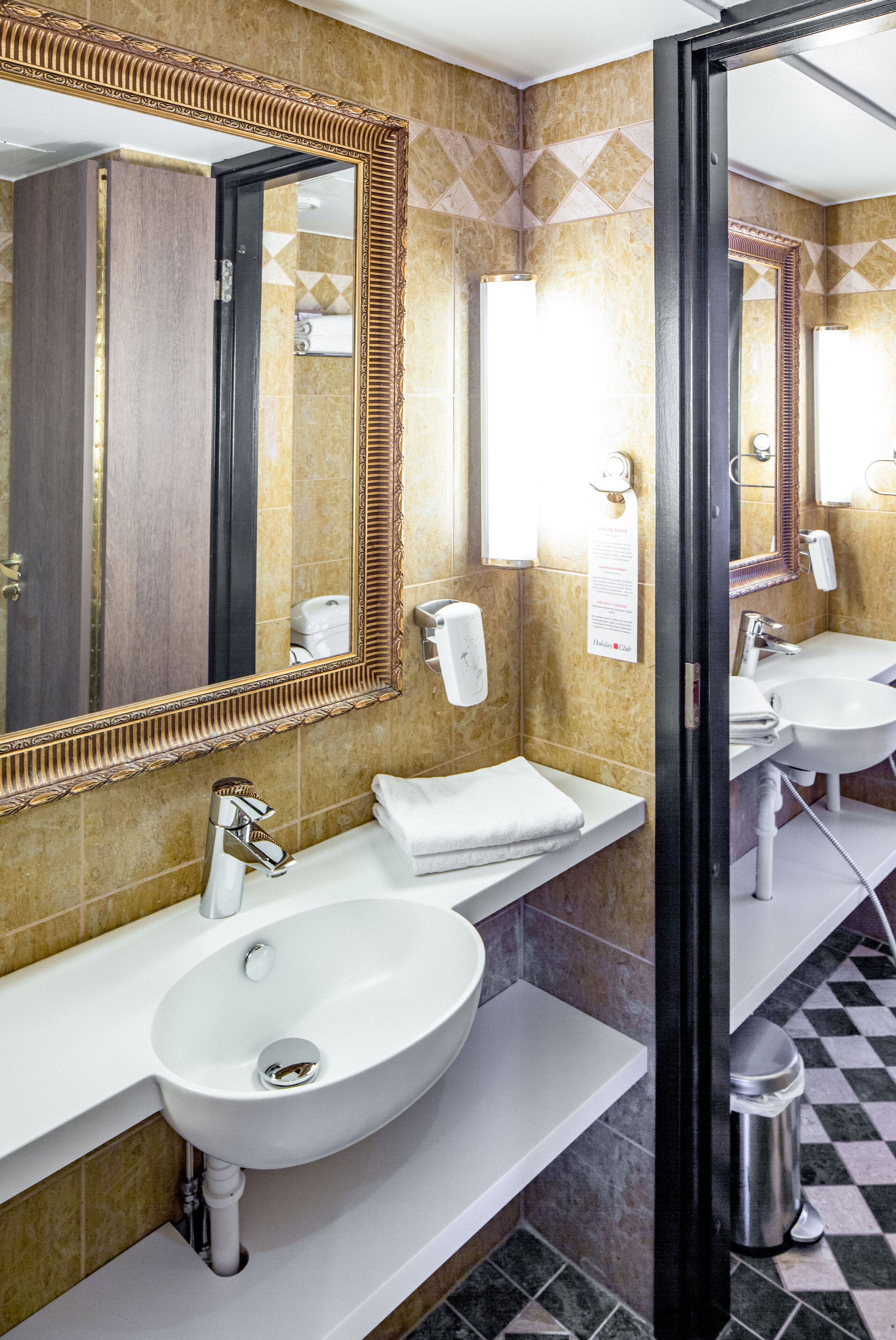 A bathroom with a white sink, a large mirror, and a towel rack.