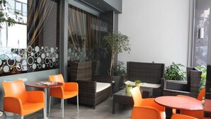 Un espacio exterior moderno con mobiliario de mimbre y sillas naranjas.