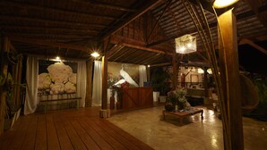 A spacious indoor area with a wooden floor, a stage with a floral backdrop, and a large white sculpture. - House of Love at Pai (Pai)