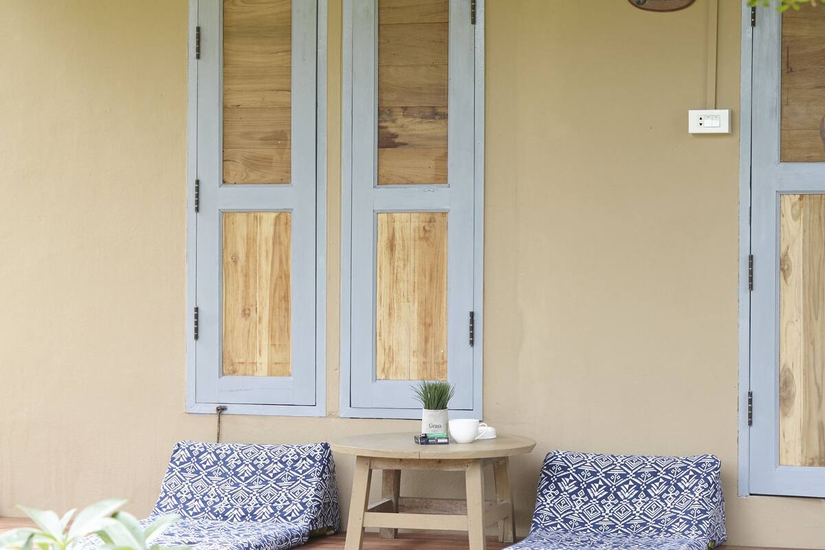 A cozy outdoor seating area with a table and chairs, surrounded by greenery and a wooden deck.