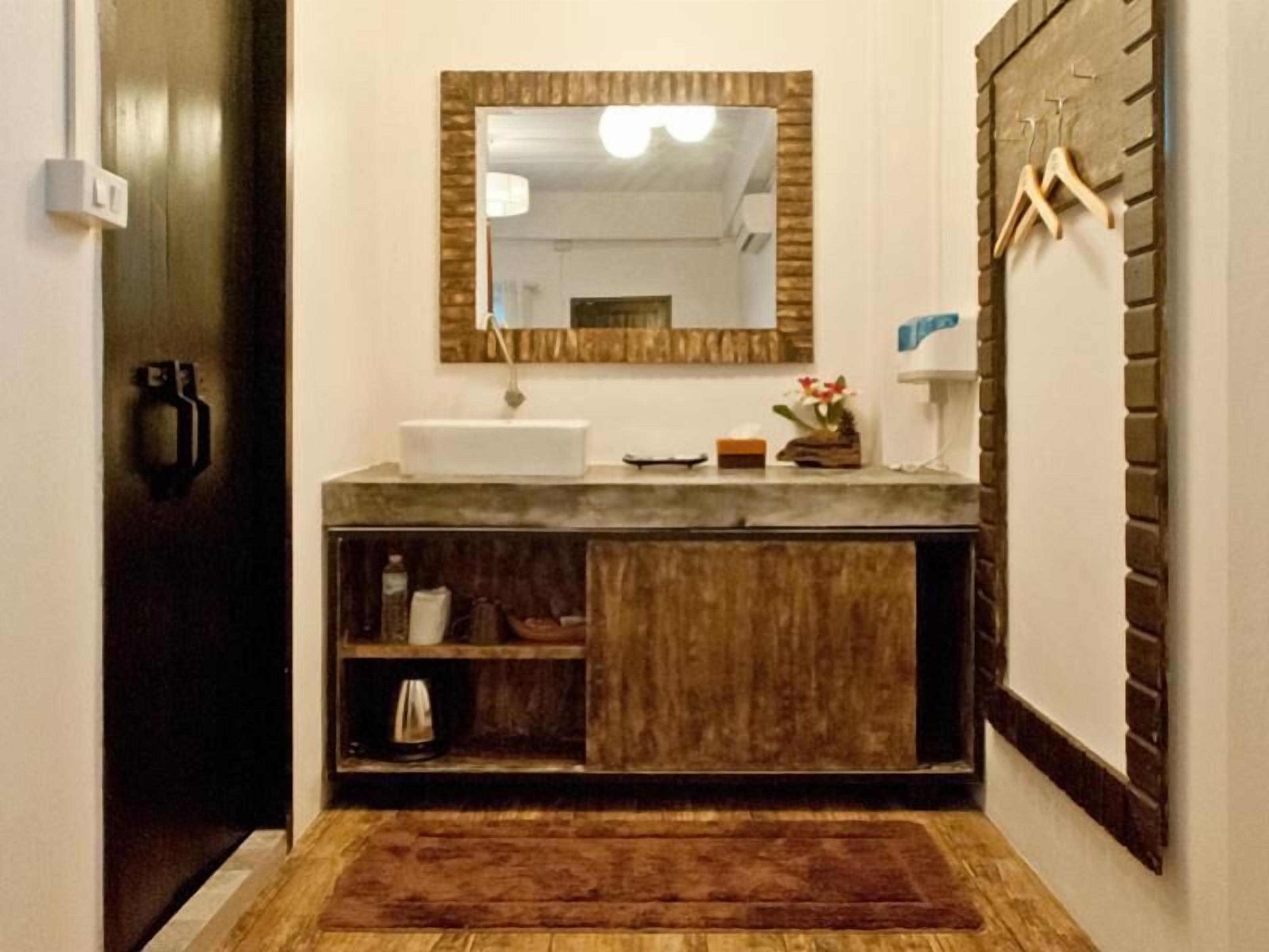 A bathroom with a wooden vanity, a mirror, a towel rack, and a small shelf with toiletries.