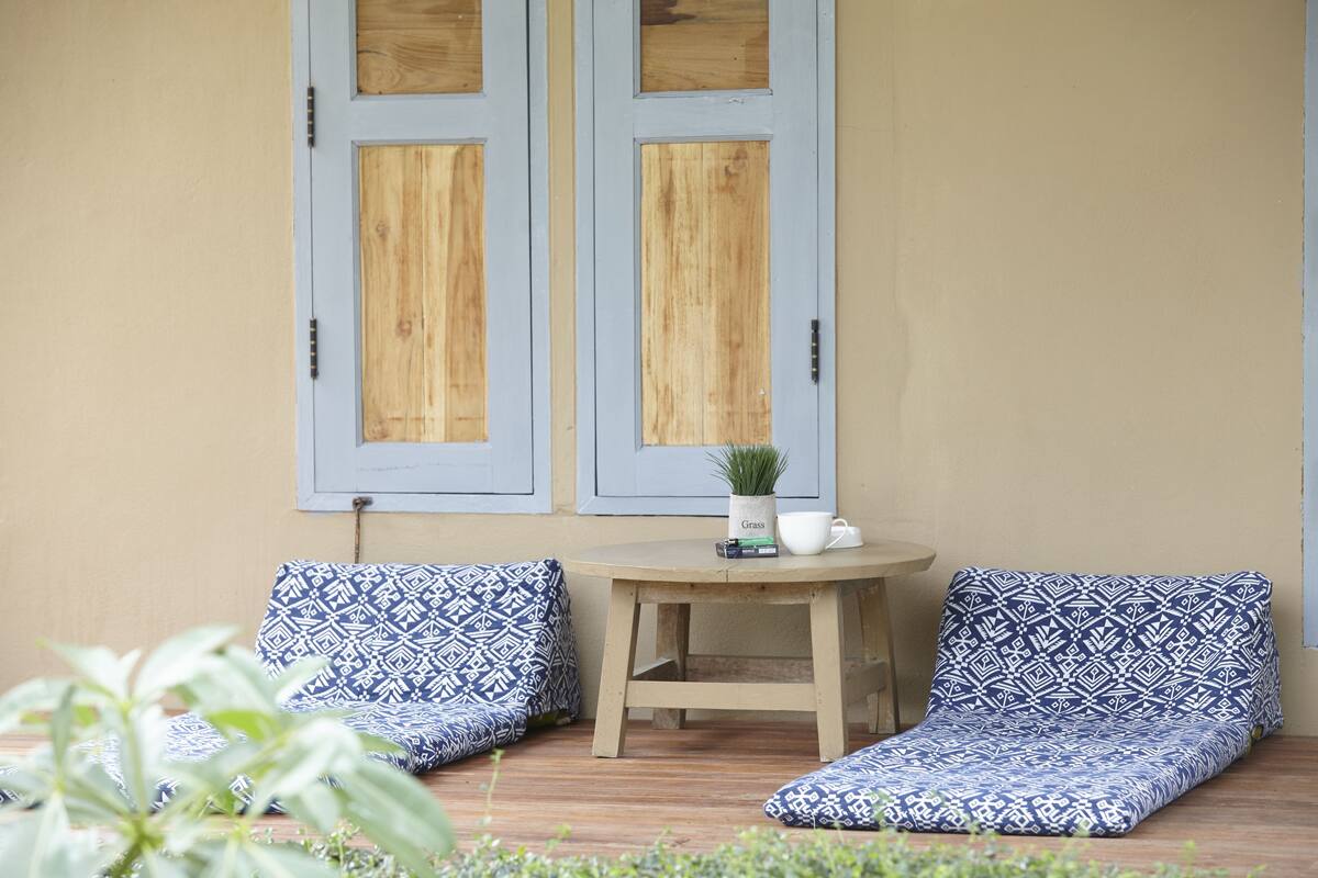 A cozy outdoor seating area with two blue patterned cushions, a small round table, and a potted plant.