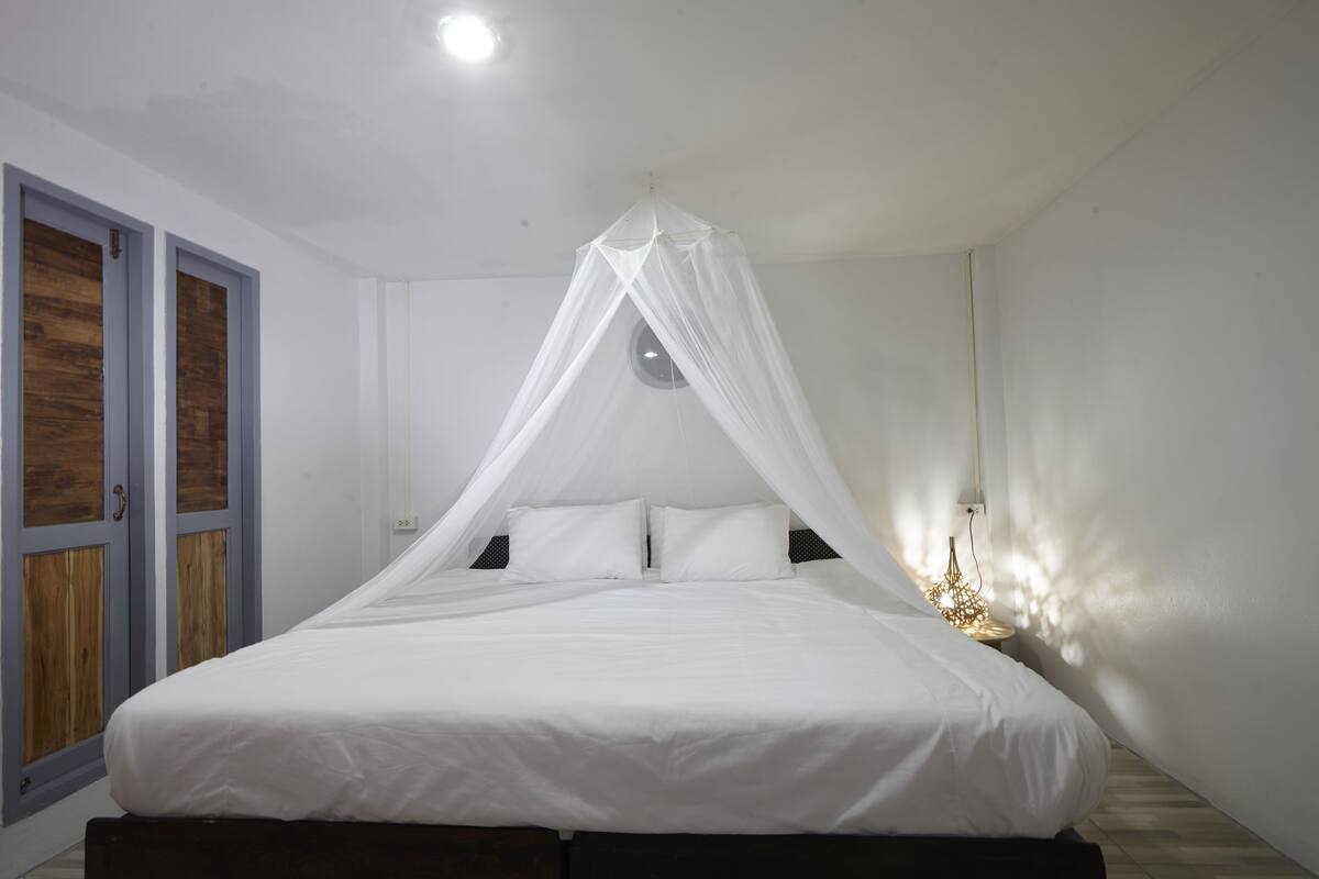 A bed with a canopy, a bedside lamp, and a wall-mounted light fixture.