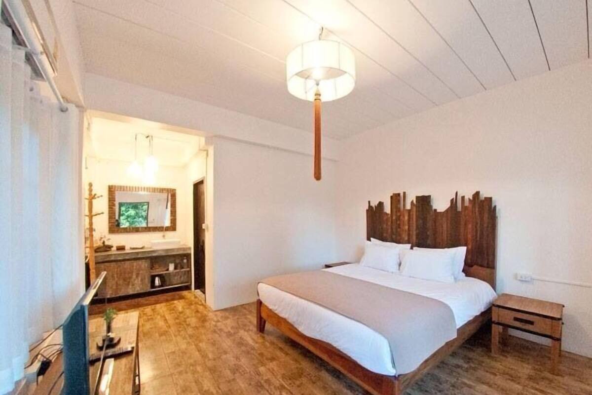 A bedroom with a wooden bed, a nightstand, a wooden dresser, and a hanging light fixture.