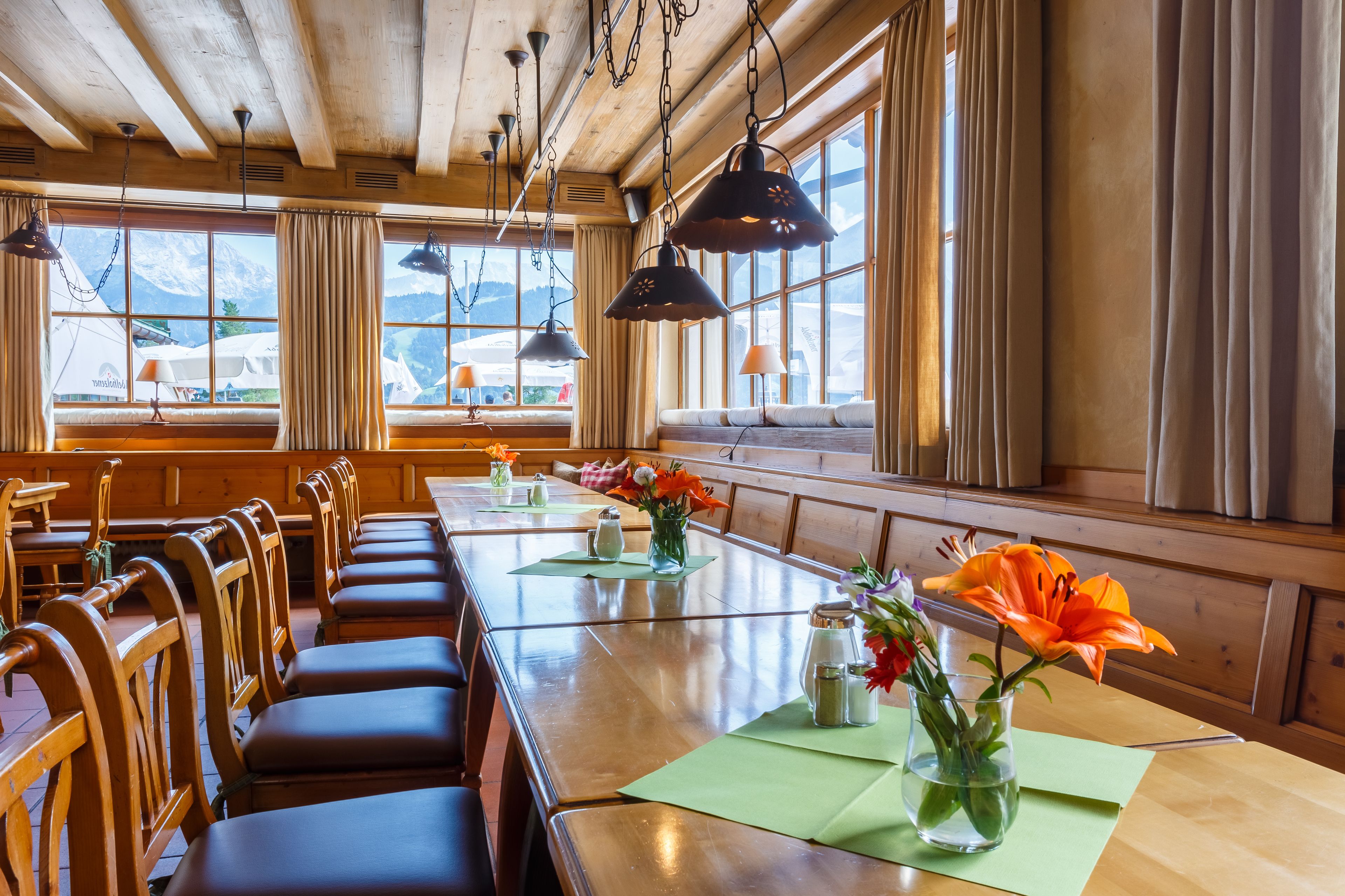 A wooden interior with a long dining table, benches, and hanging pendant lights.