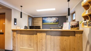 Un comptoir d’accueil avec un revêtement en bois, un tableau représentant un paysage accroché au mur et un panneau avec du texte.