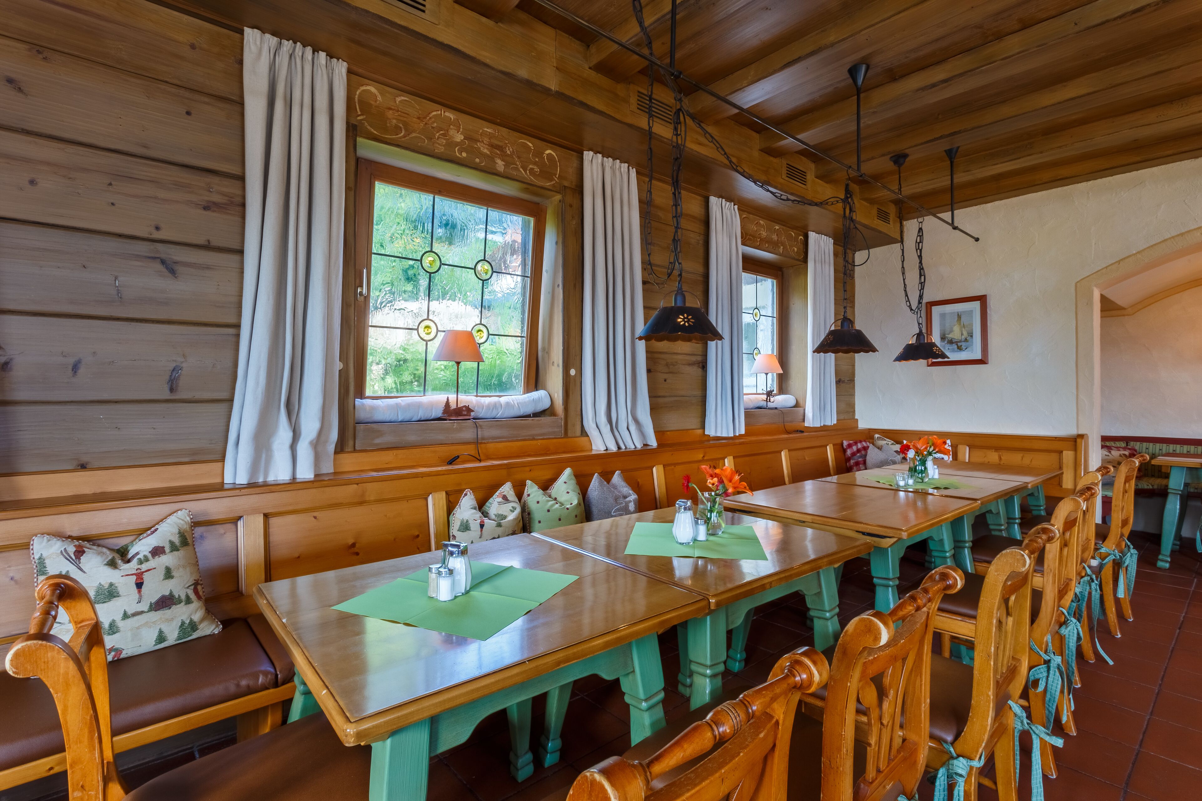 Un interior de madera con una larga mesa de comedor, bancos e lámparas colgantes.