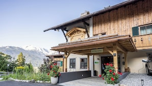 Un bâtiment en bois avec une enseigne indiquant « EINGANG » (entrée) et une vue sur des montagnes en arrière-plan.