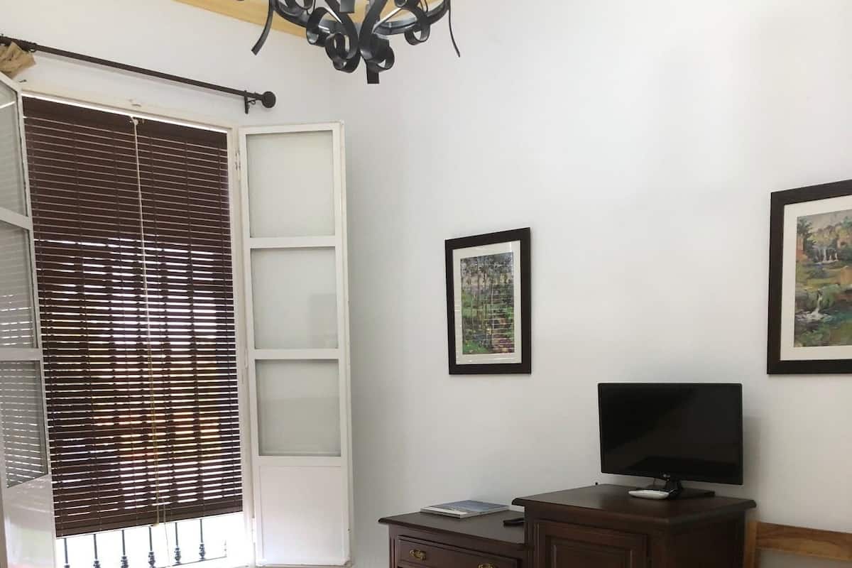 A bedroom with a bed, a desk with a computer, a chair, and a window with blinds.
