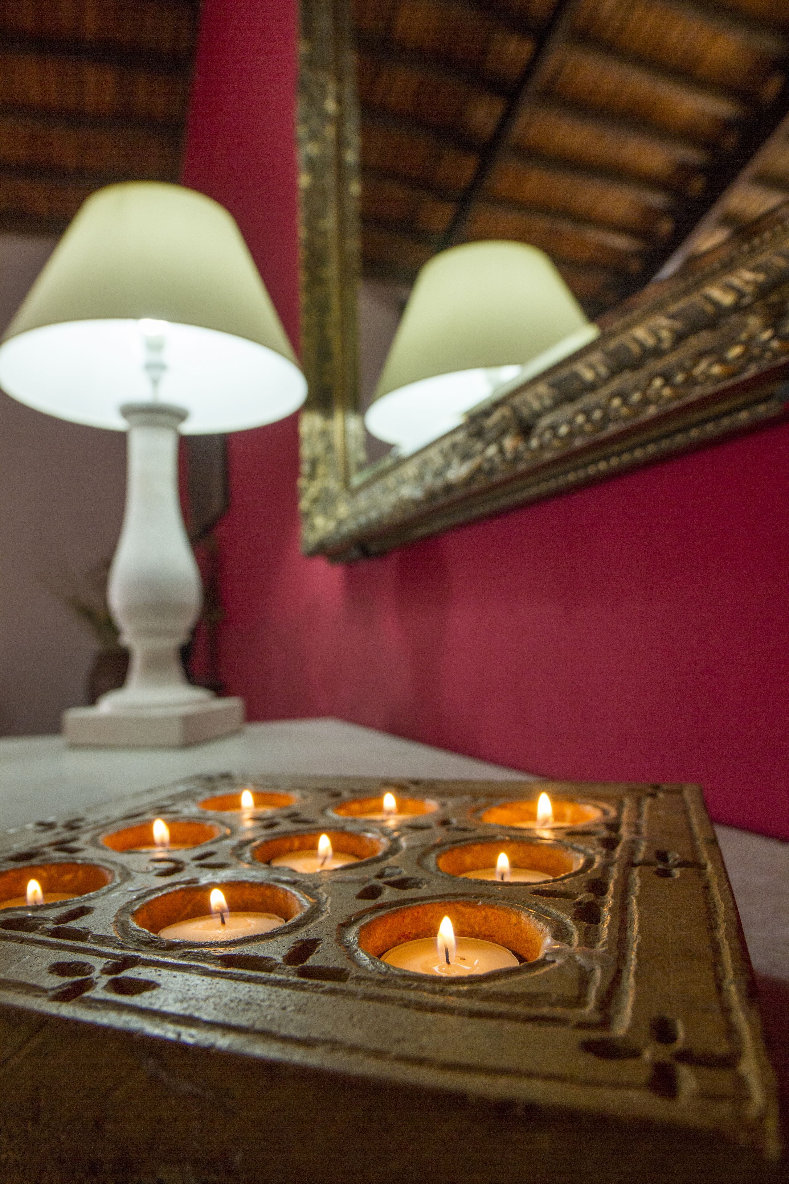 Un chandelier avec plusieurs bougies, une lampe blanche et un miroir posés sur une table.