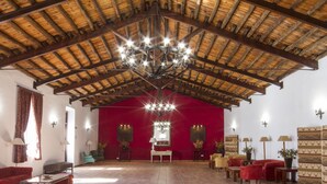 A spacious room with a high wooden ceiling, a chandelier, red walls, and multiple seating areas.